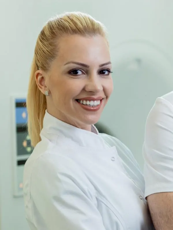 Odontóloga sonriendo con uniforme blanco